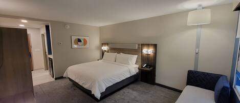 A modern hotel room with a large bed, bedside tables, a desk, and a chair.