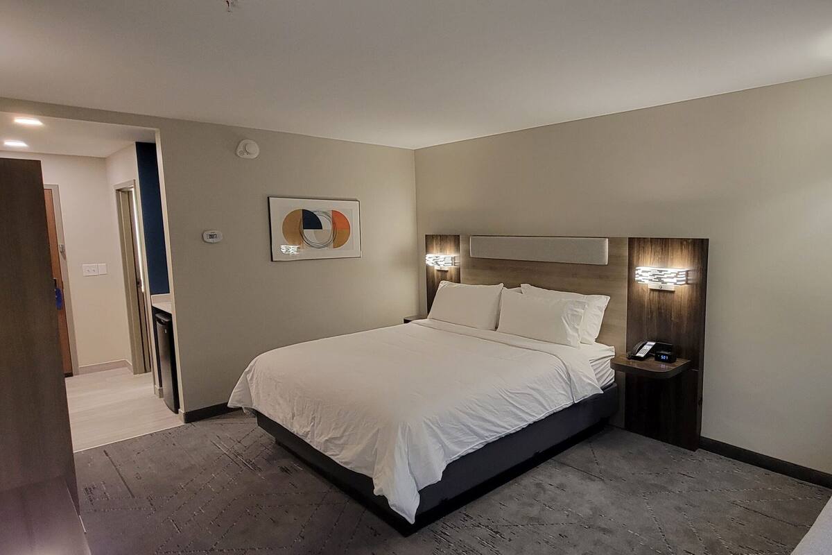 A modern hotel room with a large bed, bedside tables, a desk, and a chair.