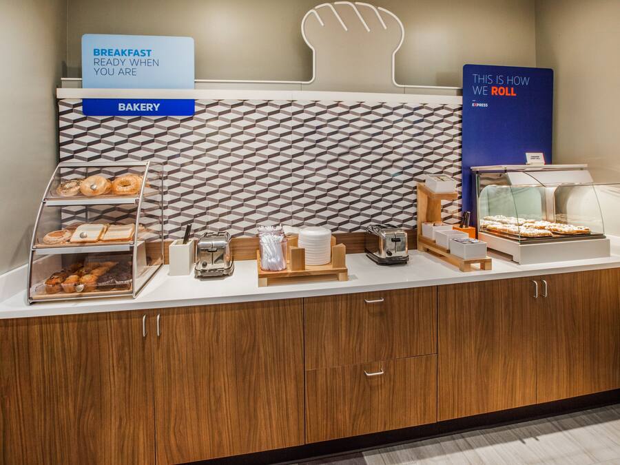 A bakery counter with various baked goods and a sign indicating breakfast is ready.