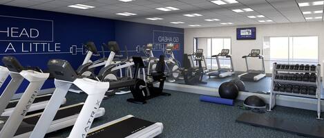 Un gimnasio moderno con cintas de correr, elípticas y pesas libres.
