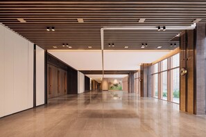 Un hall d’entrée spacieux, doté d’un plancher poli, d’un design de plafond moderne et de grandes fenêtres offrant une vue sur l’extérieur.