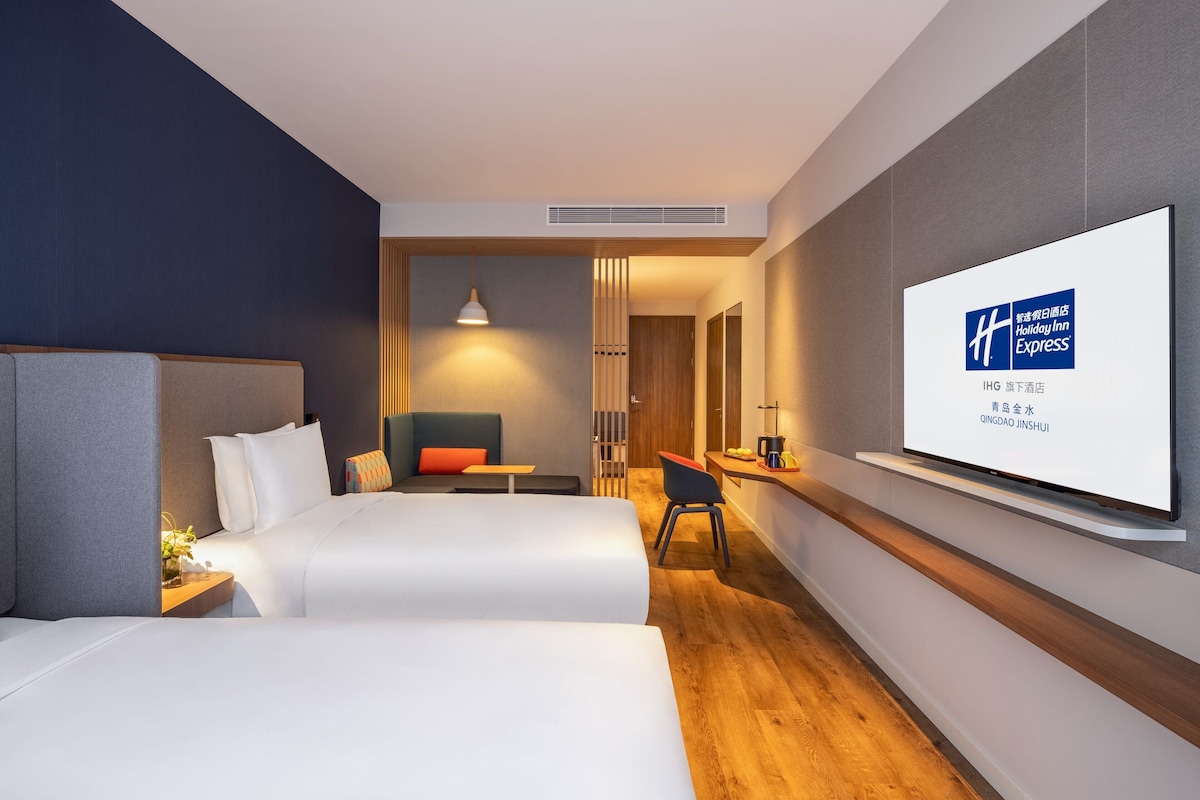 Une chambre d’hôtel avec deux lits, une télévision, un bureau et une chaise.