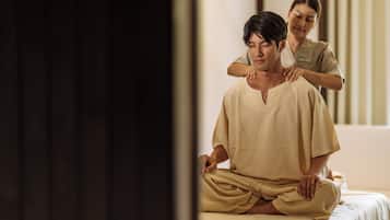 A person receiving a massage in a room with a bed and a window.