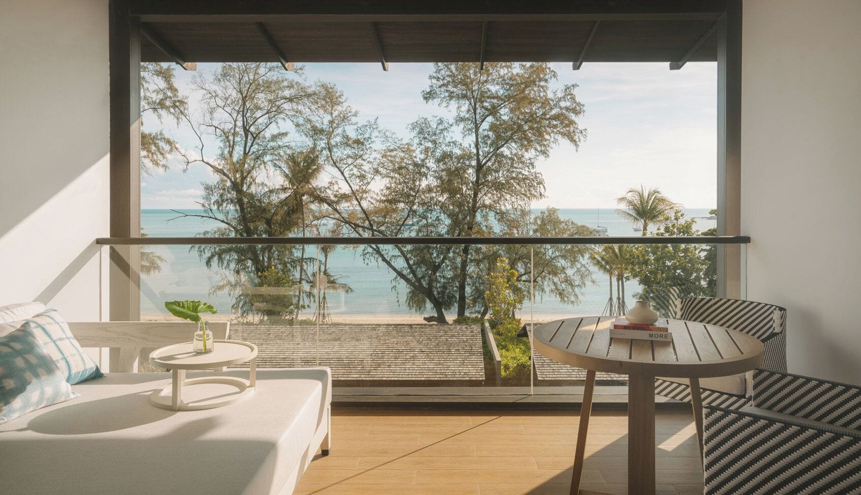 Un balcón con vistas al mar, una mesa redonda, un sofá y una silla.