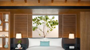 A bedroom with a bed, two bedside tables, a nightstand, a window with shutters, and a potted plant.