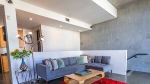 Un salon moderne avec un canapé gris, un tapis rouge et une table basse en bois.