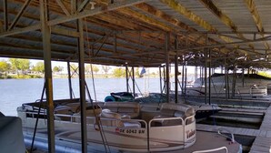 A pontoon boat docked at a pier with a covered area overhead. - Groveport Resort/Waterfront Cabin C/Newly Remodeled (Grove)