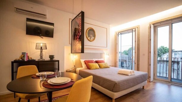 A hotel room with a bed, a dining table, chairs, a TV, and a balcony with a view. - Lemago Porto Apartments - POVEIROS 2B (Porto)
