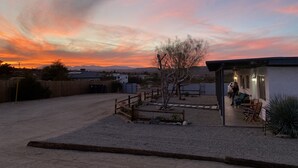 A desert landscape with a clear sky, a small tree, and a building with a covered patio.