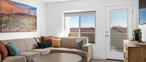 A modern living room with a sectional sofa, a round coffee table, and a ceiling fan.