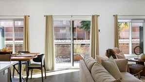 A living room with a sofa, a dining table, and a view of a building with balconies. - Spacious and Affordable Townhome, 5 BD/4.5 BA at The Vue in St. George (St. George)
