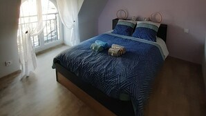 Un dormitorio con cama, ventana con cortinas y lámpara en el techo.
