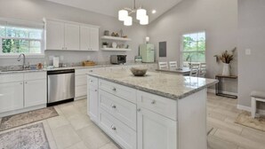 A modern kitchen with white cabinetry, granite countertops, and a central island.