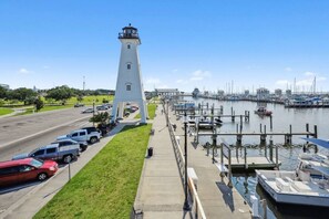 Un phare, un port de plaisance, des voitures garées et une zone herbeuse.