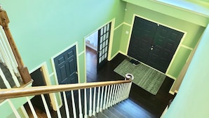 Eine Treppe mit weißen Geländern und schwarzen Türen, die zu einem Raum mit Fenster und Tür führt.