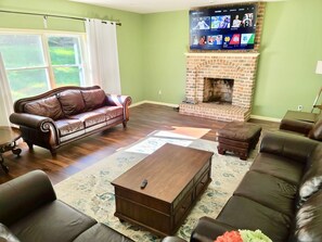 A living room with a leather sofa, a wooden coffee table, and a brick fireplace.