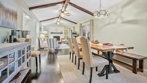 A dining area with a wooden table, cushioned chairs, and a hanging light fixture.