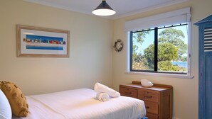 Una camera da letto con un letto, una cassettiera, una finestra vista e un quadro appeso al muro.