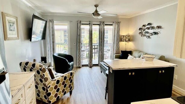 A spacious living area with a sofa, a coffee table, and a TV mounted on the wall. - Luxury Beach Living at Ocean Villa B241 (Hilton Head Island)