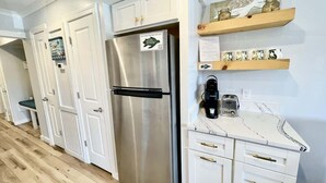A modern kitchen with white cabinetry, a stainless steel refrigerator, and a marble countertop. - Luxury Beach Living at Ocean Villa B241 (Hilton Head Island)
