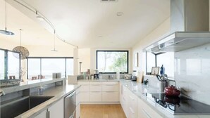 A modern kitchen with a large window, white cabinetry, and a black countertop.