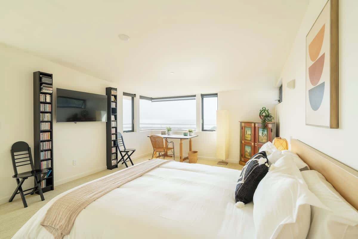 A bedroom with a large bed, a desk, and bookshelves.