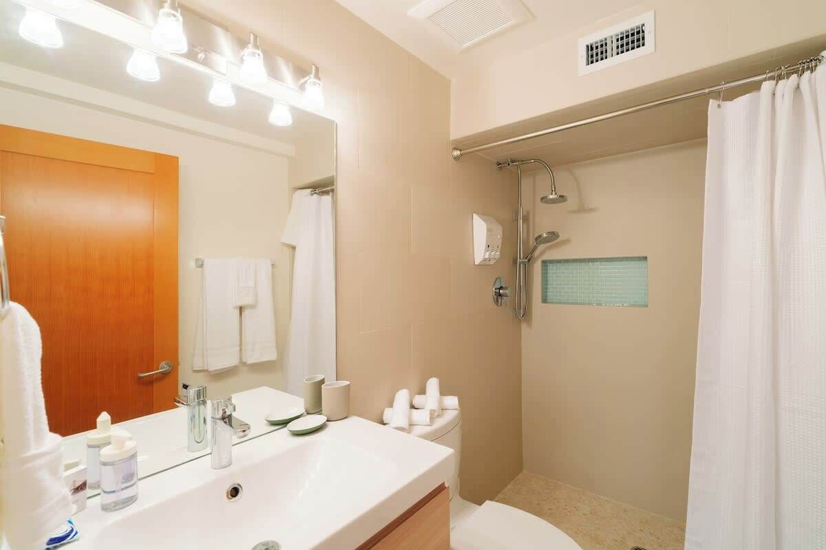 A bathroom with a sink, mirror, shower, and toilet.