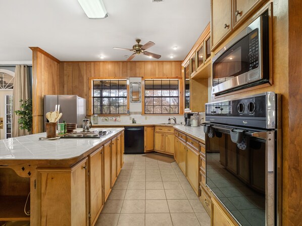 Una cocina moderna con armarios de madera, un refrigerador de acero inoxidable, un microondas y un horno empotrado.