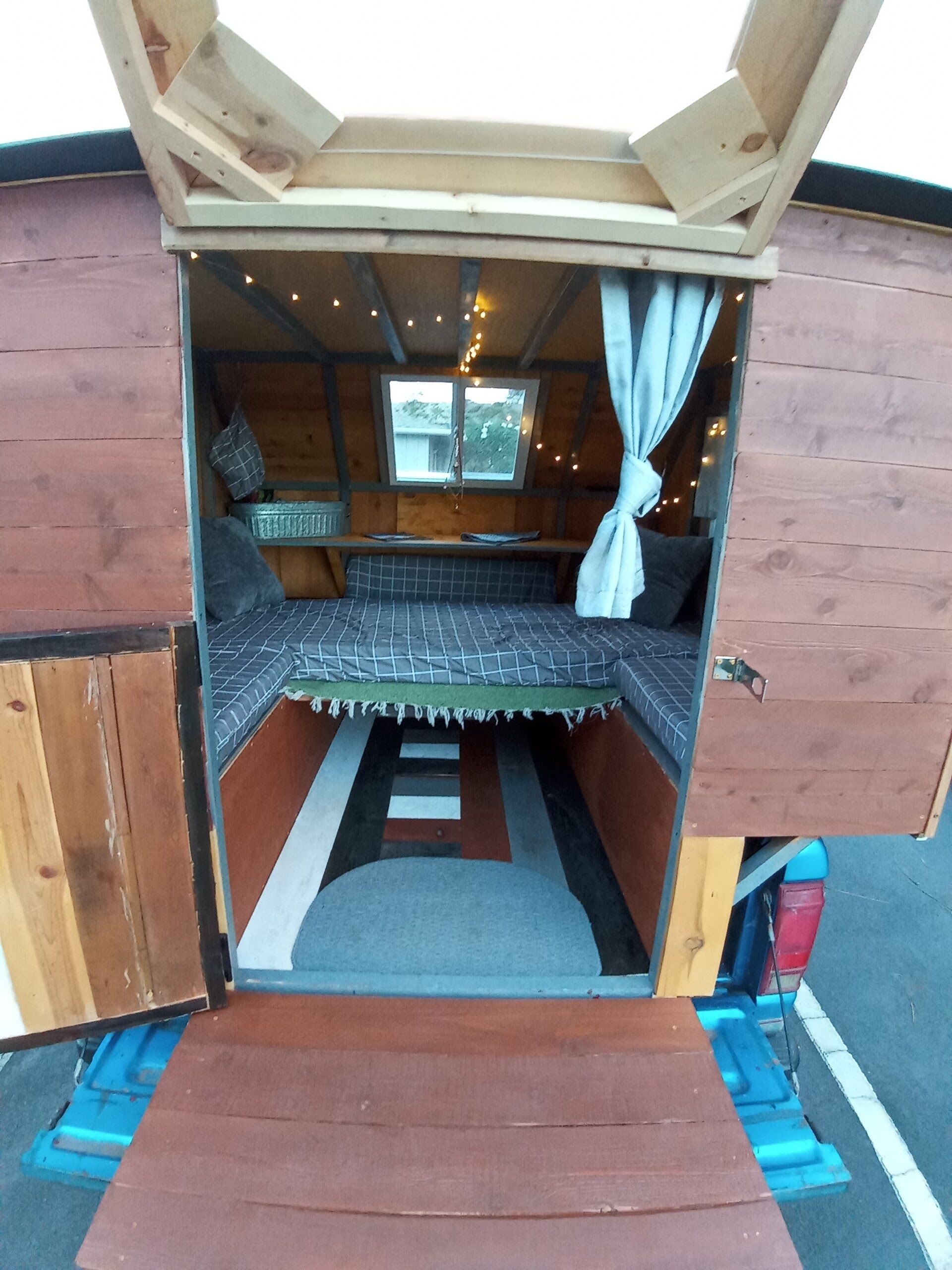 A cozy, compact room with a bed, a small table, and a window.