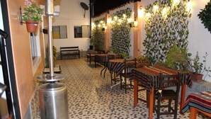 A cozy dining area with patterned floor tiles, wooden tables with colorful tablecloths, and potted plants. - KAARO House Cusco (Cusco)