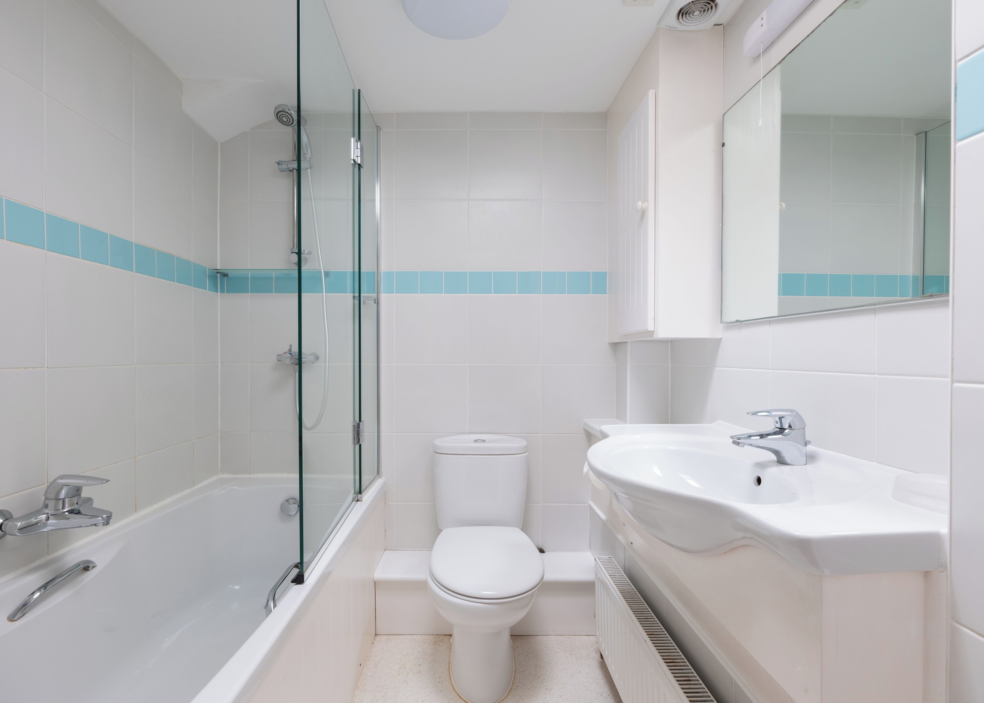 Ein modernes Badezimmer mit einer gläsernen Dusche, einer weißen Toilette und einem Waschbecken mit Spiegel darüber.