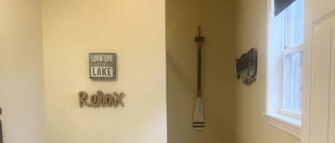 A bathroom with a toilet, a sink, and a shower area. There is a sign on the wall and a window with a view.