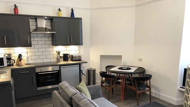 A modern kitchen with grey cabinets, a built-in oven, and a compact dishwasher.