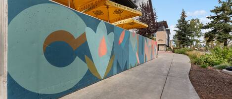 A building with a colorful mural and yellow umbrellas.