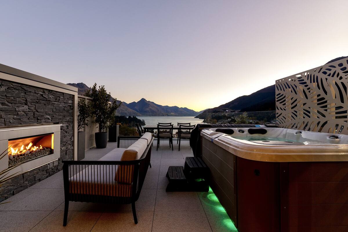 Een terras buiten met een stenen haardvuur, een zithoek en een jacuzzi.