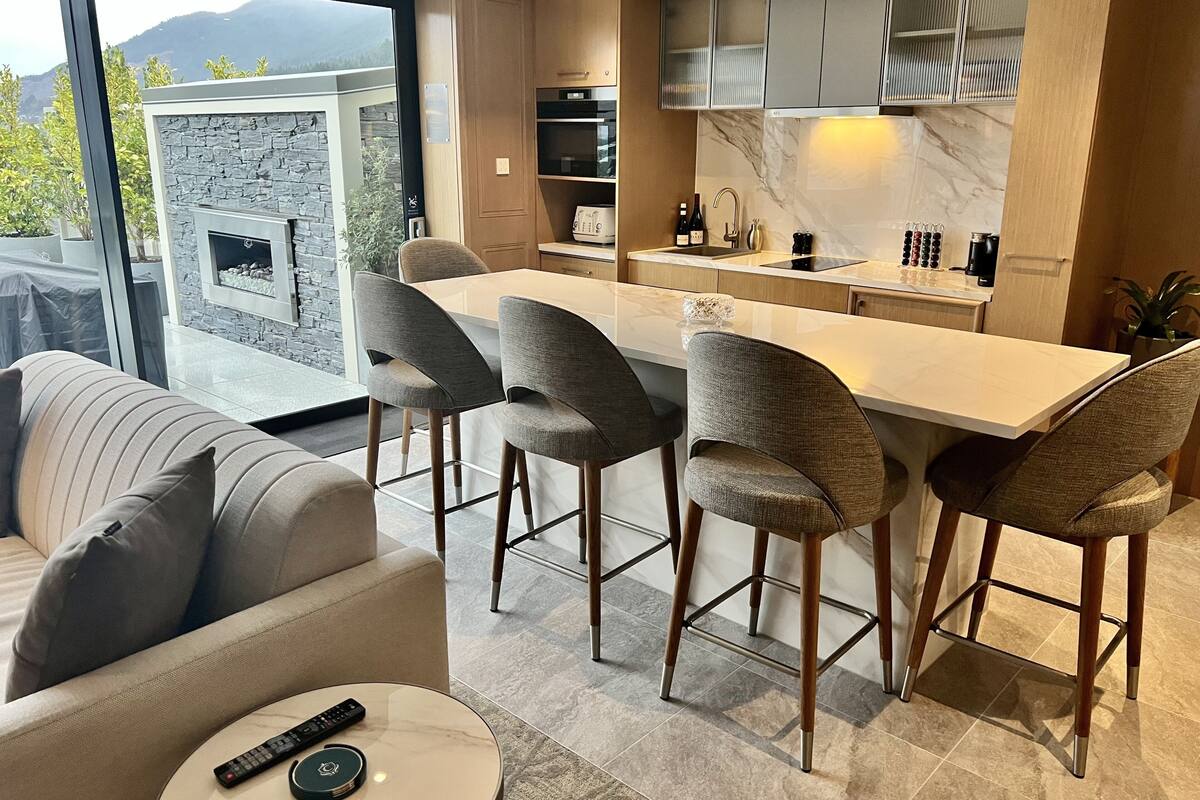 Een moderne keuken met een centraal eiland, barstoelen en een eettafel.