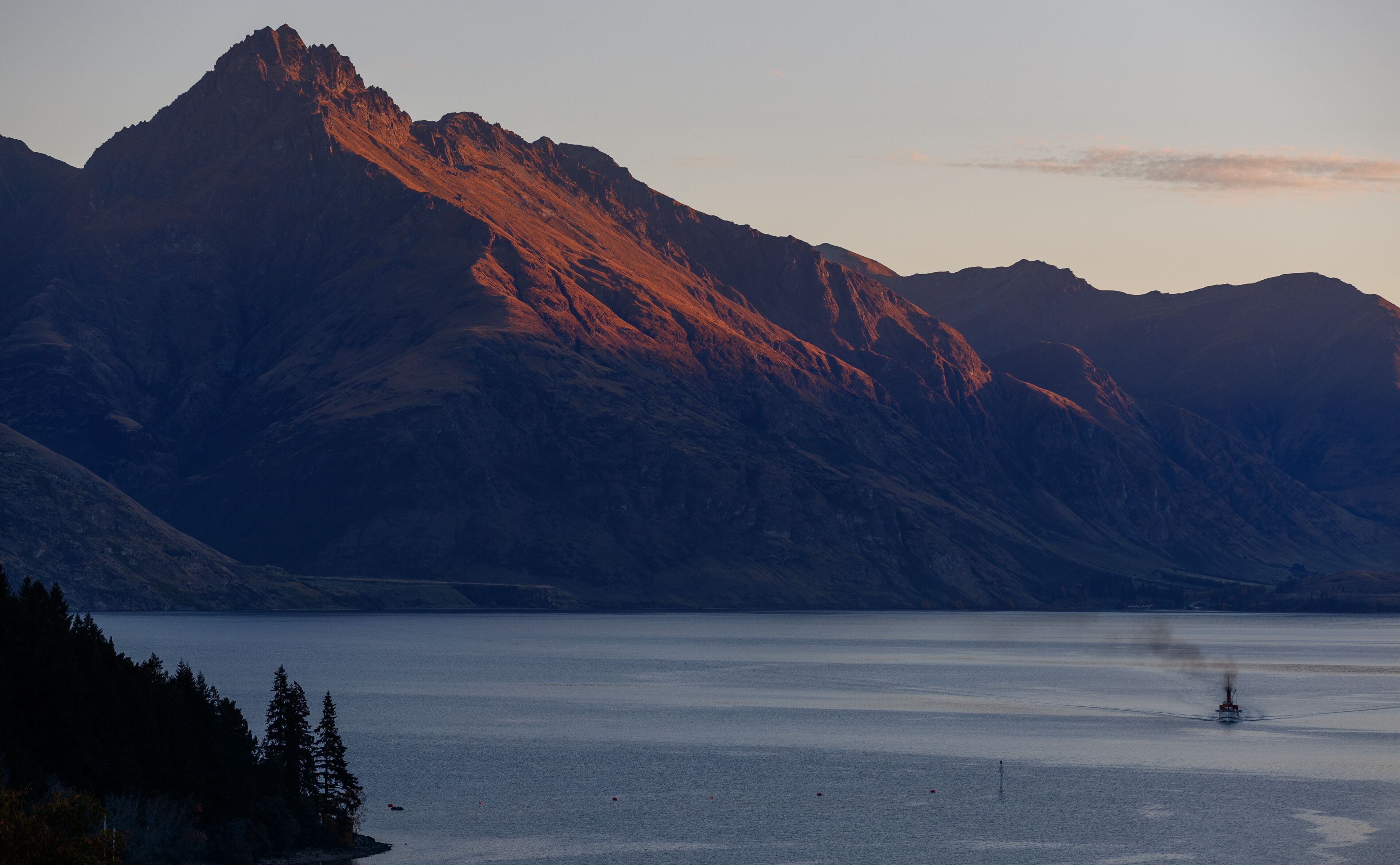 Un paysage de montagne avec un lac paisible et un bateau sur l’eau.