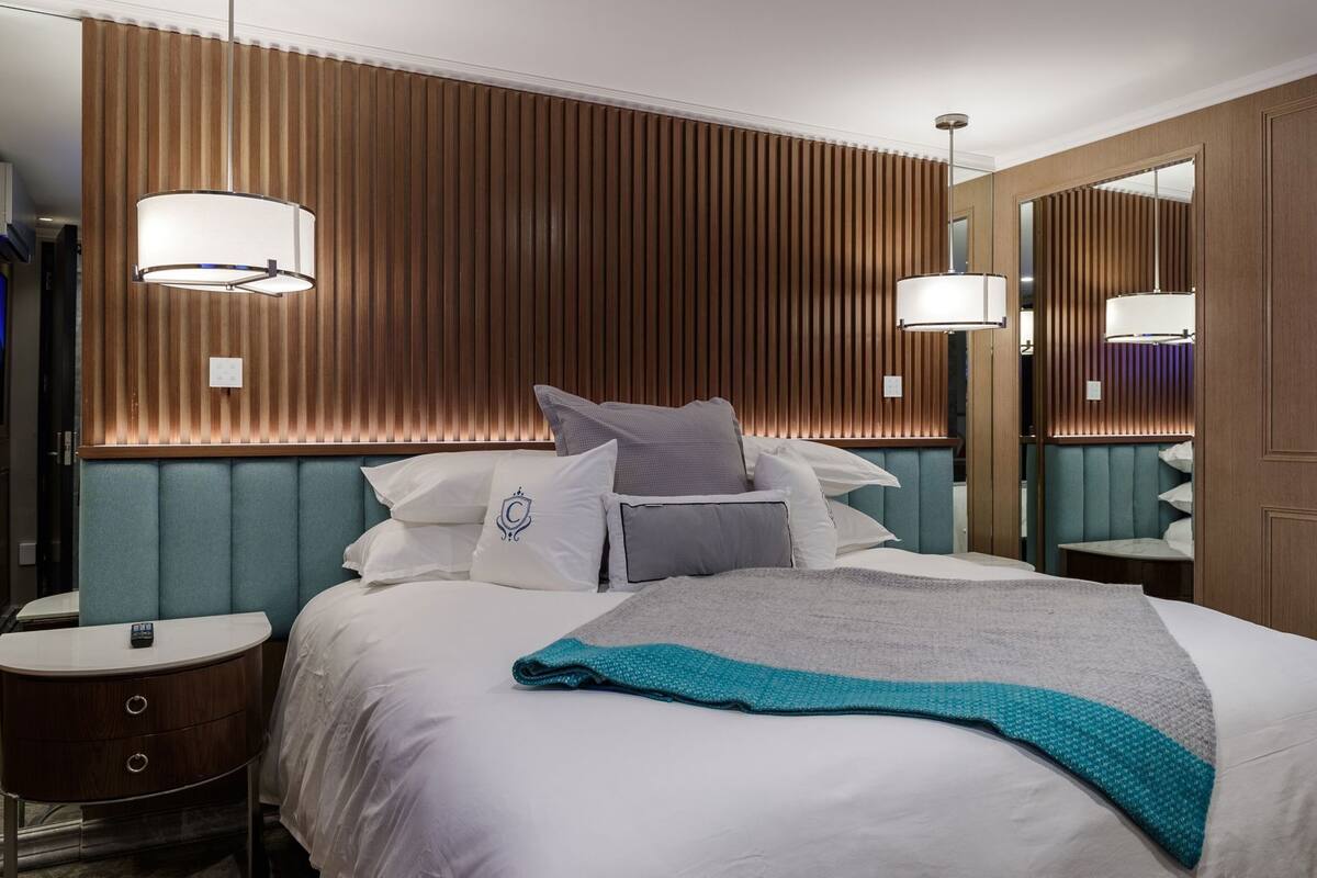 Een hotelkamer met een bed, nachtkastjes, een spiegel en een houten wandpaneel.