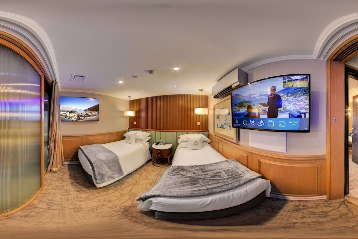 Een hotelkamer met twee bedden, een televisie, een bureau en uitzicht op een stadsbeeld.