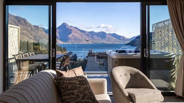 Un balcon avec vue sur les montagnes et un lac, aménagé avec un canapé et des fauteuils.