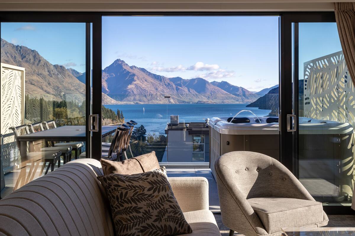 Een balkon met uitzicht op bergen en een meer, voorzien van een bank en stoelen.