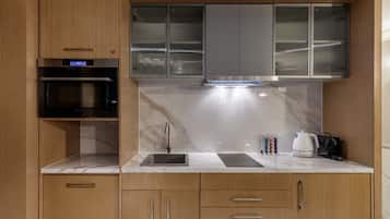A modern kitchen with wooden cabinets, a built-in oven, a stainless steel range hood, and a marble countertop.