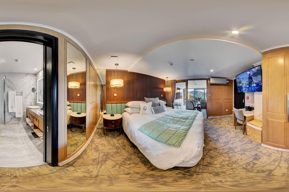 Une chambre d’hôtel comprenant un lit, des tables de chevet, une télévision, une armoire et une salle de bain avec douche.