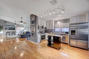 Enjoy cooking and relaxing in this well-equipped kitchen and living area with a stainless steel refrigerator, microwave, and oven.