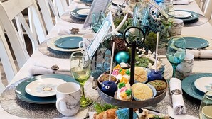 A dining table set with plates, glasses, and a tiered dessert stand.