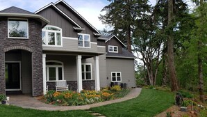 A two-story house with a stone facade, large windows, and a well-maintained garden.