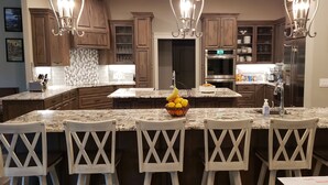 A kitchen with wooden cabinets, granite countertops, and a central island with chairs.