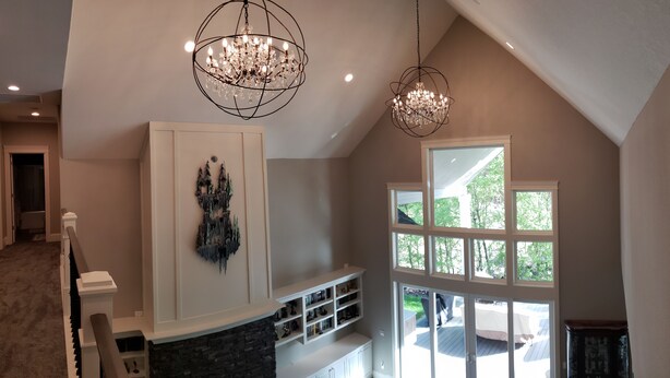 A spacious room with a high ceiling, a large window with multiple panes, and a built-in fireplace.
