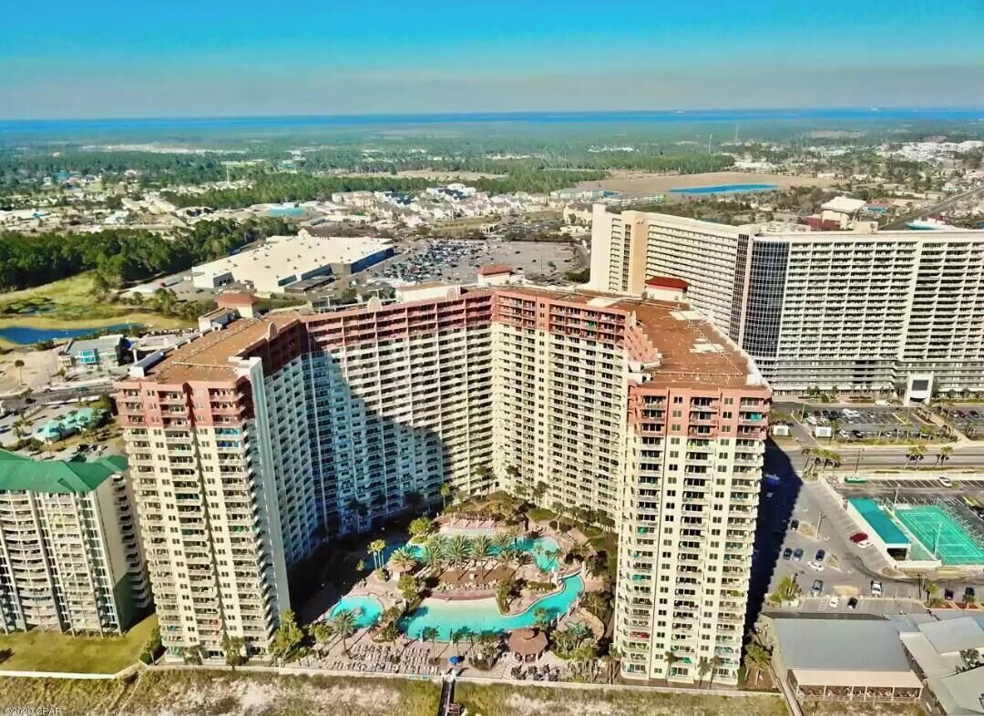 A high-rise hotel with multiple floors, a rooftop pool, and a surrounding landscaped area.