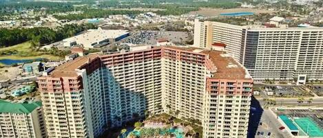 A high-rise hotel with multiple floors, a rooftop pool, and a surrounding landscaped area.